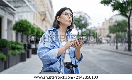 Young beautiful hispanic woman using smartphone waiting for taxi in the streets of Vienna