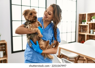 Young beautiful hispanic woman veterinarian smiling confident hugging dog at home - Shutterstock ID 2251547997