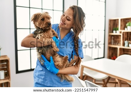 Young beautiful hispanic woman veterinarian smiling confident hugging dog at home