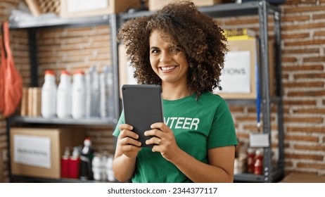 Young beautiful hispanic woman volunteer smiling confident using touchpad at charity center - Powered by Shutterstock