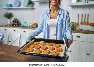 Young beautiful housewife holding freshly baked cookies on a tray in the kitchen. - Powered by Shutterstock