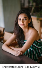 A Young And Beautiful Indian Asian Woman Sits For Her Portrait Head Shot In A Stylish Cafe During The Day. She Projects Confidence And She Looks Like She Belongs In High Society. 