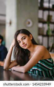 A Young And Beautiful Indian Asian Woman Sits For Her Portrait Head Shot In A Stylish Cafe During The Day. She Projects Confidence And She Looks Like She Belongs In High Society. 