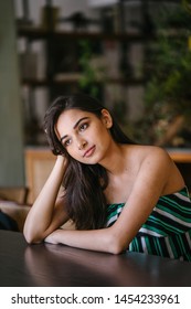 A Young And Beautiful Indian Asian Woman Sits For Her Portrait Head Shot In A Stylish Cafe During The Day. She Projects Confidence And She Looks Like She Belongs In High Society. 