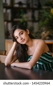 A Young And Beautiful Indian Asian Woman Sits For Her Portrait Head Shot In A Stylish Cafe During The Day. She Projects Confidence And She Looks Like She Belongs In High Society. 