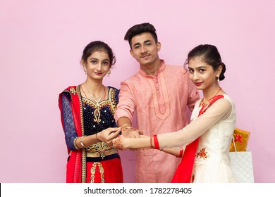 Young Beautiful Indian Brother Sister celebrating Rakshabandhan or Bhai dooj tying Rakhi, Showing money, laughing cheering, Enjoying and eating sweets.Selective Focus (Rakshabandhan/Bhai dooj Concept)