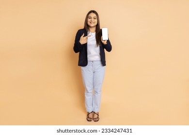 Young beautiful indian businesswoman wearing formal suit showing smart phone with blank display screen to put advertisement isolated over white background. Corporate Concept. - Powered by Shutterstock