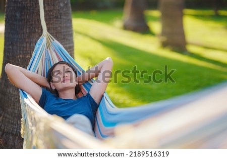 young beautiful lady posing while lying on hammock, beautiful asian woman, brunette resting on vacation, relax, outdoor portrait. long weekend and vacation holidays spent slow life in Turkey