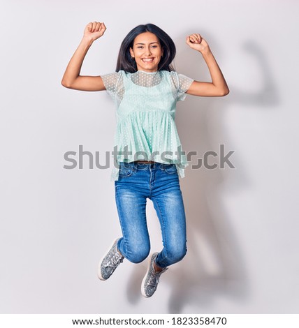 Young beautiful latin woman wearing casual clothes smiling happy. Jumping with smile on face over isolated white background