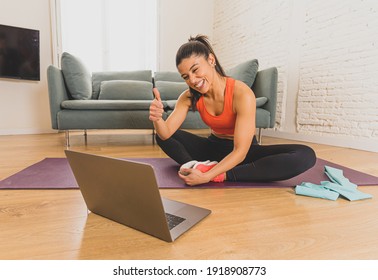 Young Beautiful Latin Woman Working Out At Home Connected To Online Fitness Class On The Computer Laptop. Woman Personal Trainer Coach On Zoom Teaching Exercises In Live Streaming Workout Class.