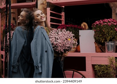 Young beautiful laughing woman holding bouquet of chrysanthemum in pot at florist store against flowers background. Customer, buyer. Saleswoman. Woman florist. Small business. Floral shop. - Shutterstock ID 2394409149