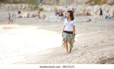 Young beautiful lone girl walking on a crowded beach.