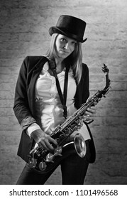 Young beautiful long haired blonde in black hat with saxophone. Black and white . - Shutterstock ID 1101496568