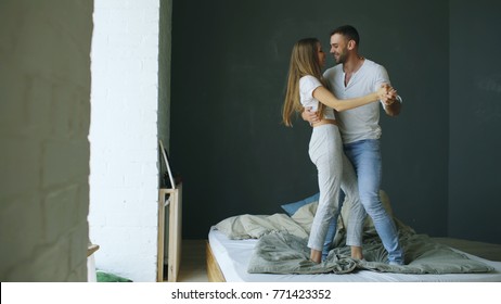 Young beautiful and loving couple dancing on bed in morning