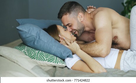Young beautiful and loving couple kissing on bed in the morning