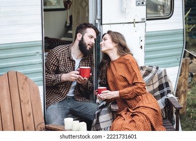 Young Beautiful Loving Couple Travelling Across Country In The Van. Millennial Man And Woman In A Travel Camper. Cozy Atmosphere, Vacations Vibe. Drinking Tea, Cooking Marshmallow On A Campfire