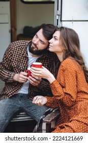 Young Beautiful Loving Couple Travelling Across Country In The Van. Millennial Man And Woman In A Travel Camper. Cozy Atmosphere, Vacations Vibe. Drinking Tea, Cooking Marshmallow On A Campfire