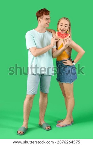 Young beautiful man and woman with slice of fresh watermelon on green background