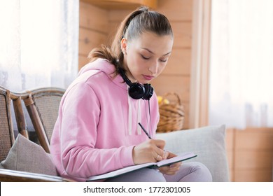 Young Beautiful Millennial Woman In Casual Wear Studying At Home, Draws Sketch, Writing Notes In Notebook, Makes Plans, Creative Freelancer Writes To-do List In Diary. Self-education, Planning Concept