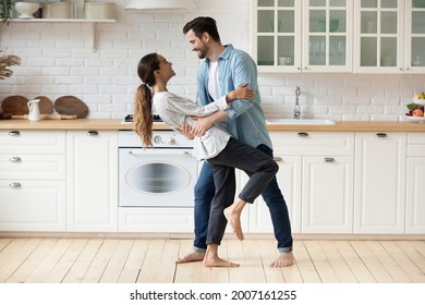 Young beautiful mixed race couple home owners family celebrate relocation day housewarming dancing in modern cozy kitchen standing barefoot on warm floor feel happy. Romance, dating, bank loan concept - Powered by Shutterstock