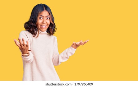 Young beautiful mixed race woman wearing winter turtleneck sweater smiling cheerful with open arms as friendly welcome, positive and confident greetings  - Shutterstock ID 1797960409