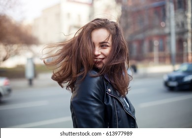 Jovem modelo linda sorri e olha para trás na cidade. Dinamicamente jovem caminha pela rua. Cabelo tremulando ao vento.