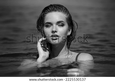               Young beautiful model posing in the water on a sunny day and looking at the camera.black and white                  