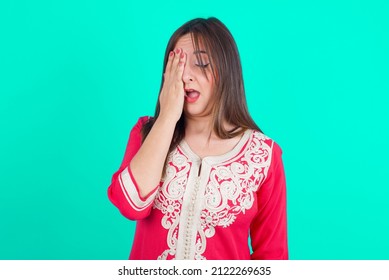 Young Beautiful Moroccan Woman Wearing Traditional Caftan Dress Over Green Background Yawning Tired Covering Half Face, Eye And Mouth With Hand. Face Hurts In Pain.