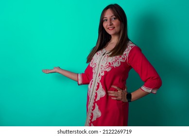young beautiful moroccan woman wearing traditional caftan dress over green background feeling happy   cheerful  smiling   welcoming you  inviting you in and friendly gesture
