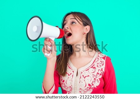 young beautiful moroccan woman wearing traditional caftan dress over green background Through Megaphone with Available Copy Space