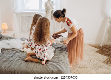 Young beautiful mother is bringing cocoa with Marshmallows and cookies to her daughters sitting on the bed in the full of light cozy room - Shutterstock ID 1254337030