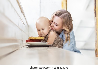 Young Beautiful Mother Feeds Her Little Baby With Harmful Sweet Food. The Concept Of Malnutrition Children And Excess Of Desserts For Kids