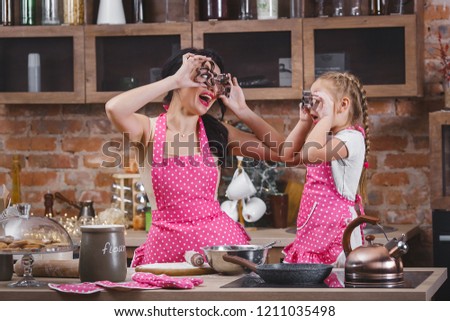Young beautiful mother and her little daughter cooking together at the kitchen
