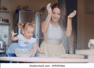 joven y hermosa madre enseña a su hija a preparar la masa en la cocina Foto de stock