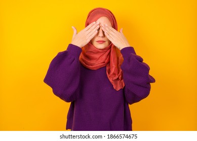 Young Beautiful Muslim Woman Wearing Hijab Against Yellow Background Covering Eyes With Both Hands, Doesn't Want To See Anything Or Feeling Ashamed. Human Feelings Reactions.
