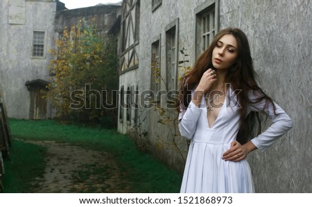 Young beautiful mysterious girl in white dress in old medieval town