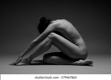 Young beautiful nude woman practicing yoga on a dark background