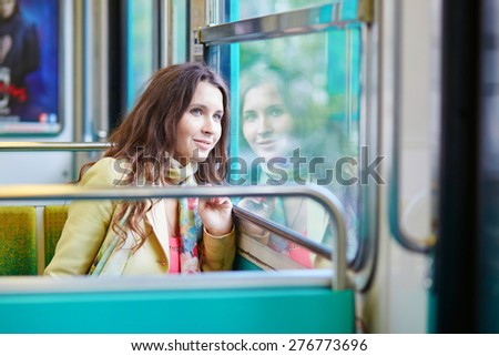 Young beautiful Parisian woman traveling in a subway train, sitting near the window