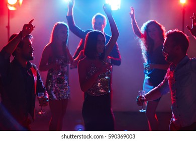 Young beautiful people hanging out in popular night club, dancing with hands up and smiling cheerfully - Shutterstock ID 590369003