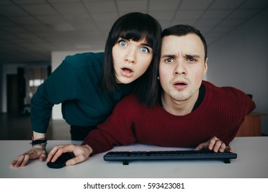 Young Beautiful People Puzzled Look In The Computer Monitor. Emotional Look At The Camera