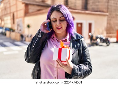 Young beautiful plus size woman talking on the smartphone holding gift at street - Shutterstock ID 2254774581