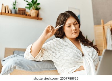 A young, beautiful plus size woman thoughtfully interacts with her laptop while relaxing at home. - Powered by Shutterstock