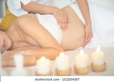 Young beautiful pregnant woman having massage in spa salon 