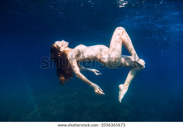 Young beautiful pregnant woman underwater in blue
        ocean