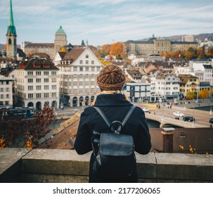 Young beautiful pretty blonde tourist girl in warm hat and coat with backpack walking at cold autumn in Europe city enjoying her travel in Zurich Switzerland - Shutterstock ID 2177206065