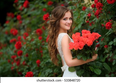 Young beautiful pretty girl with long hair and white dress standing and holding bucket red roses.