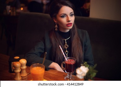 Young beautiful pretty stylish dressed formal woman looking away and drinking mulled wine