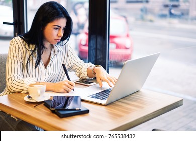 Young Beautiful Professional Female Freelancer Making Researches While Surfing In Internet During Distance Work On Laptop Computer.Pensive Copywriter Watching Training Webinar In Webpage On Gadget