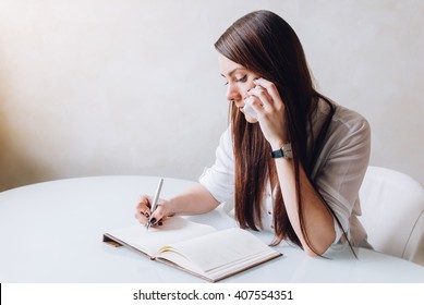 A Young Beautiful Receptionist And Personal Assistant Is Very Serious. She Is Making A Phone Call And Taking Notices As A Business Woman