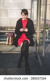 young beautiful red dressed vintage hipster woman in street town waiting bus
